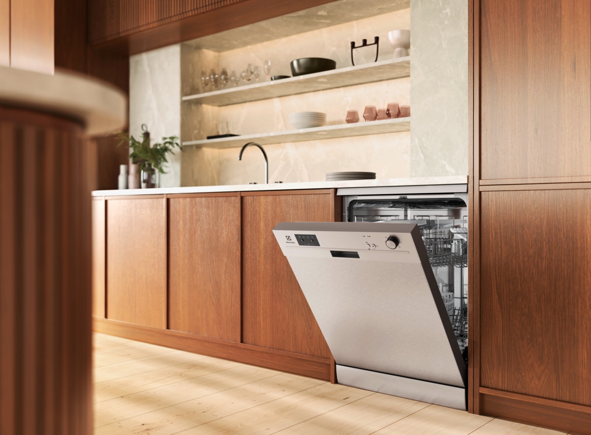 Electrolux dishwasher built under a countertop in wood-grain cabinetry with the door open showing loading racks