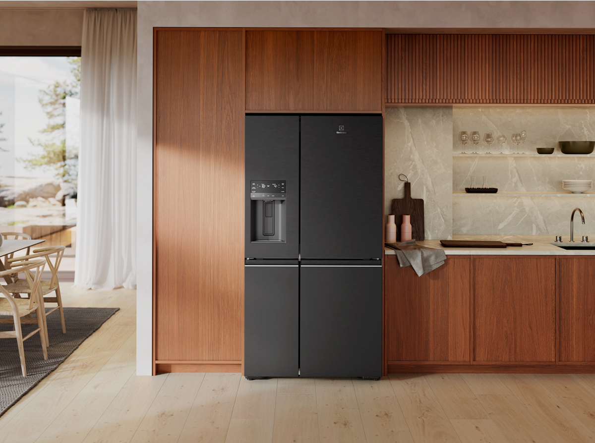Electrolux four-door refrigerator with external ice and water dispenser built into wood-tone kitchen cabinetry