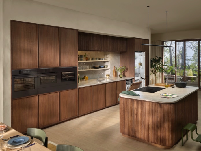 Spacious kitchen with wood cabinets, built-in ovens, a induction hob and a refrigerator.