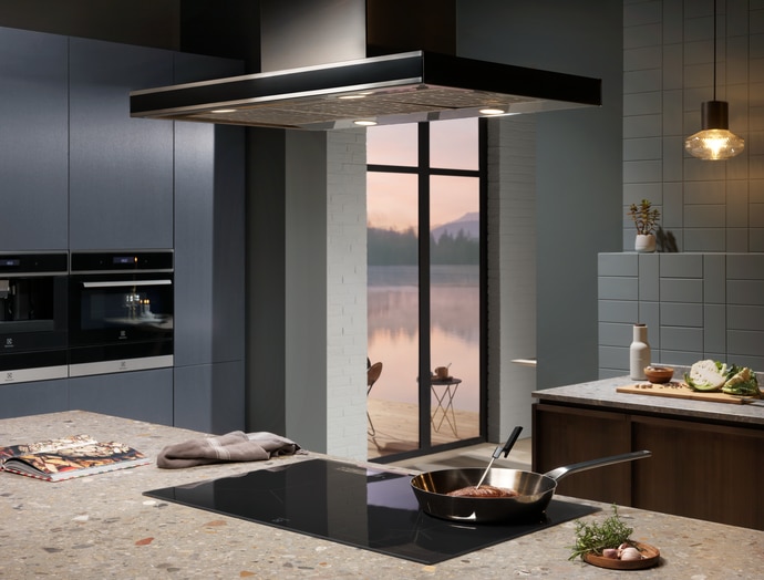 Contemporary kitchen with built in ovens, an island cooktop and a cooker hood.