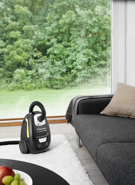 An Electrolux canister vacuum cleaner next to a sofa