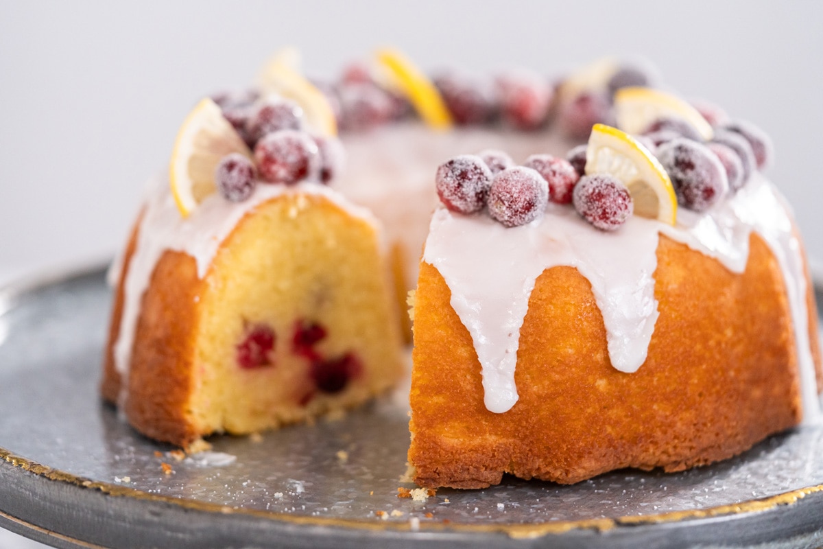 Iced bundt-style orange cake topped with sugared cranberries and lemon slices