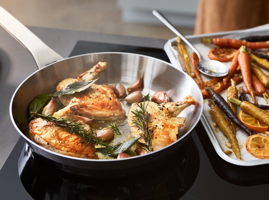 Chicken breasts searing with herbs in a pan