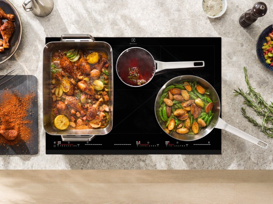 Top-down view of an Electrolux induction hob cooking multiple dishes simultaneously