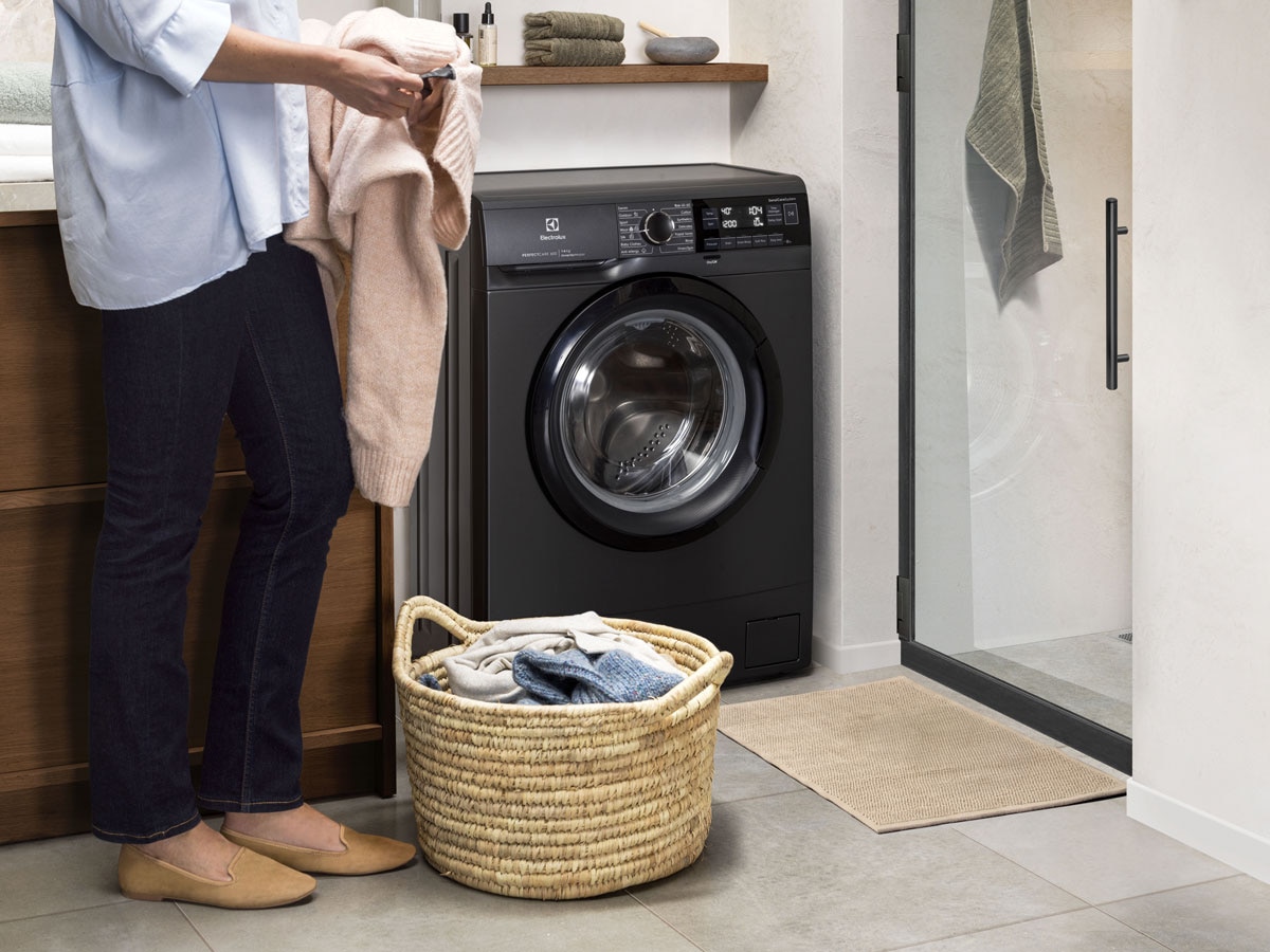 A person reading laundry care label before loading Electrolux washer