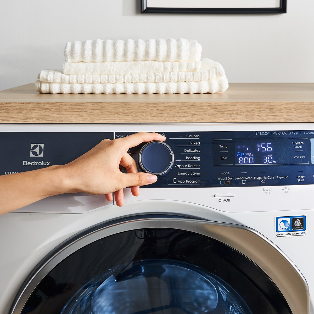 A hand selecting Electrolux washing machine setting