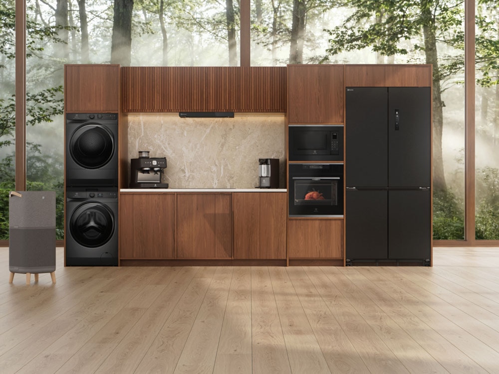 Multiple appliances set showing an Electrolux washer and dryer tower, coffee maker, built-in oven, microwave and refrigerator in a streamlined kitchen wall