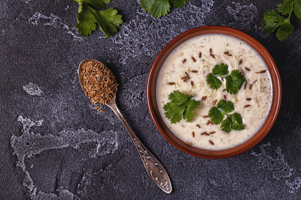 Burani raita in a bowl topped with cumin seeds and cilantro